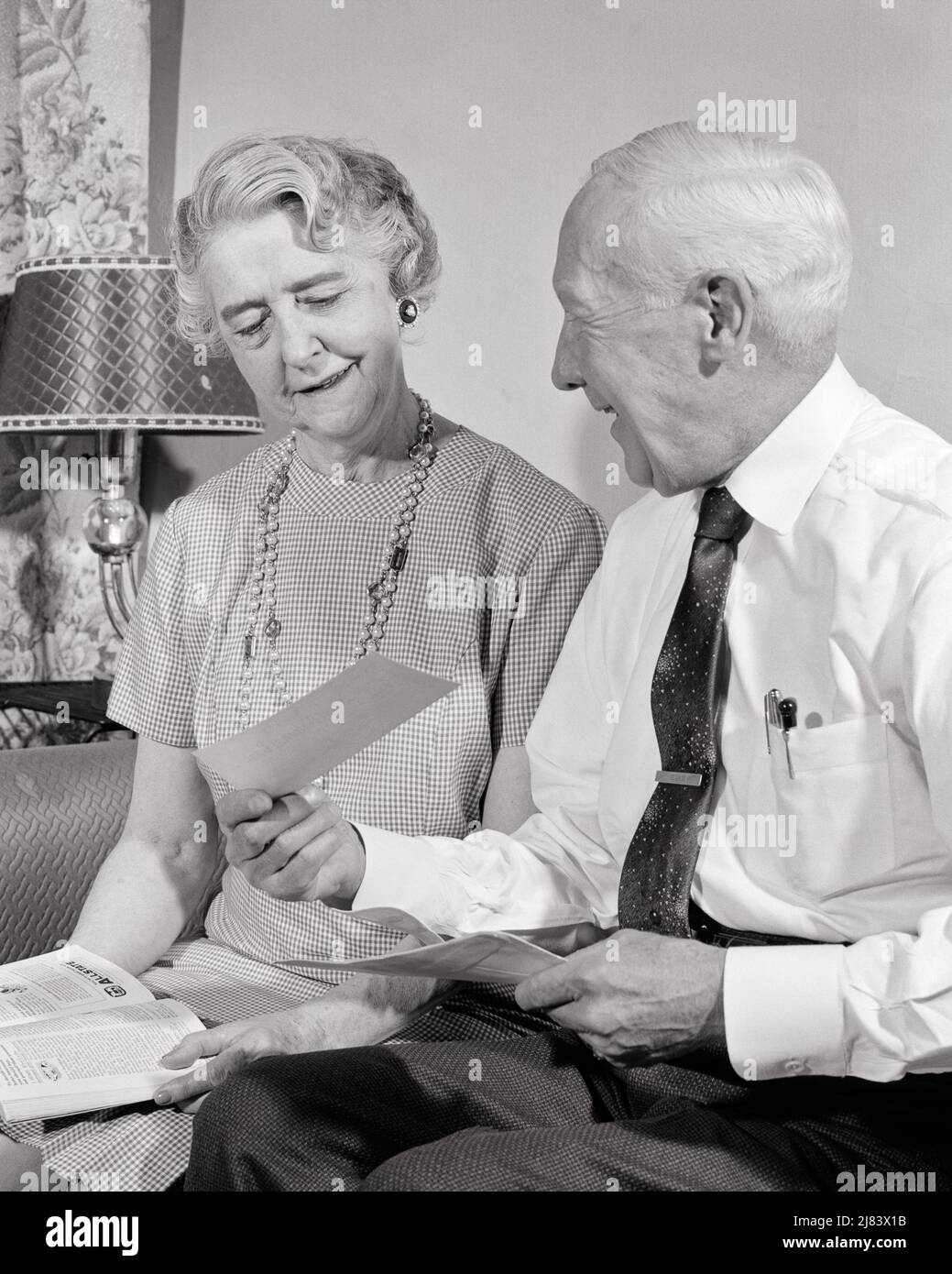 1950s coppia anziana seduta sul divano donna ha rivista in grembo uomo sorridente mostrando il suo assegno che ha appena ricevuto IN MAIL - S8291 HAR001 HARS SODDISFAZIONE ANZIANO DONNE SPOSATE MOSTRANDO CONIUGE MARITI HOME VITA COPIA SPAZIO AMICIZIA SIGNORE A MEZZA LUNGHEZZA PERSONE MASCHI SOLO PENSIONE ANZIANO UOMO B&W PARTNER GIRO ANZIANO DONNA RETIREE FELICITÀ VECCHIAIA OLDSTER ALLEGRO IN SU SORRISI ANZIANI PENSIONE GIOIOSO UOMO ANZIANO HA RICEVUTO LA SICUREZZA SOCIALE UNIONE MOGLI NERO E BIANCO ETNIA CAUCASICA HAR001 ANNI ALLA MODA Foto Stock