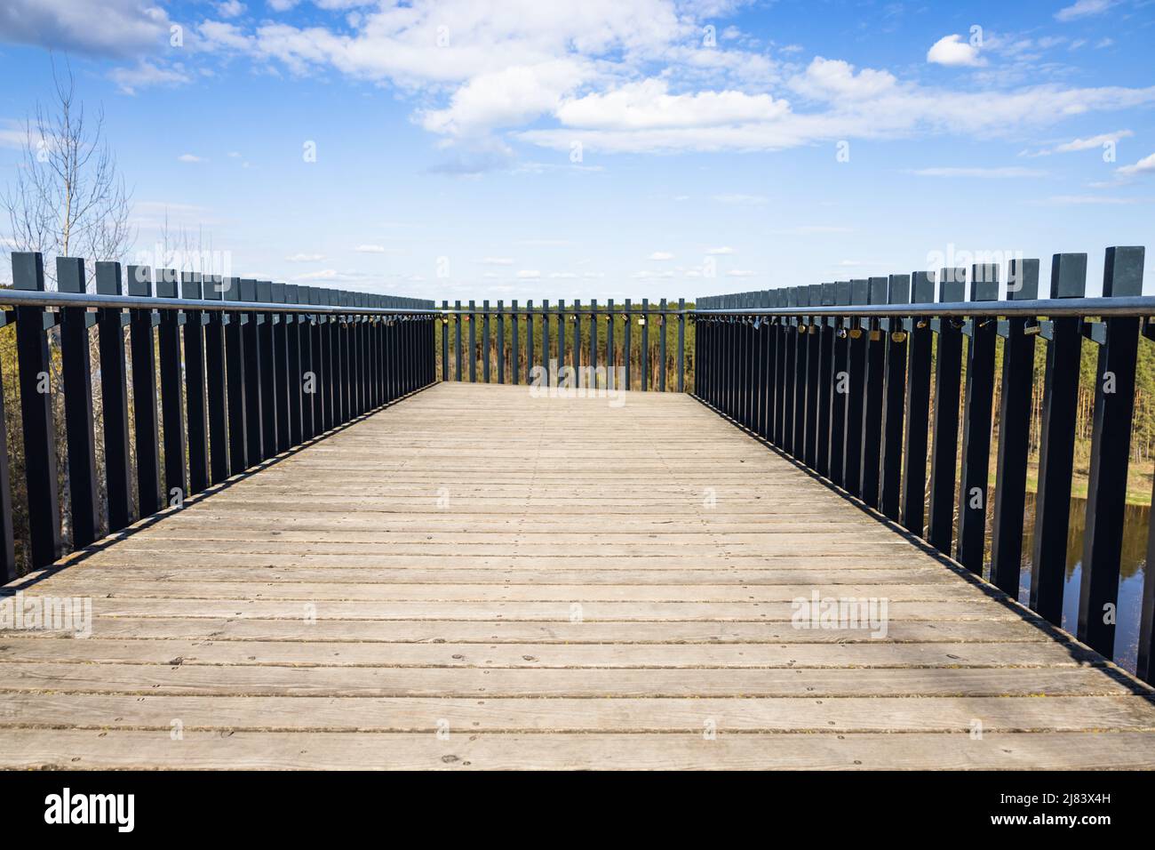 Piattaforma in legno con corrimano in acciaio e lucchetti d'amore appesi su di essa Foto Stock