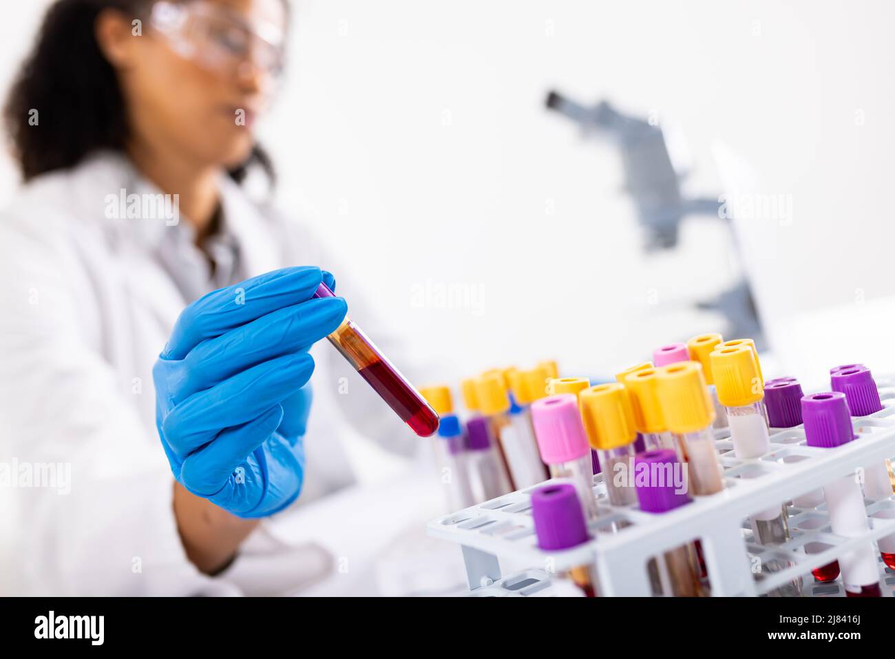 Primo piano di un guanto medico femminile afroamericano per adulti di media età che mette la provetta nel vassoio Foto Stock