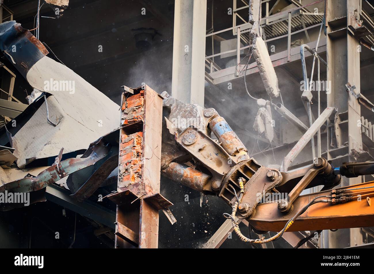 La fresa idraulica della gru demolisce il vecchio edificio industriale Foto Stock