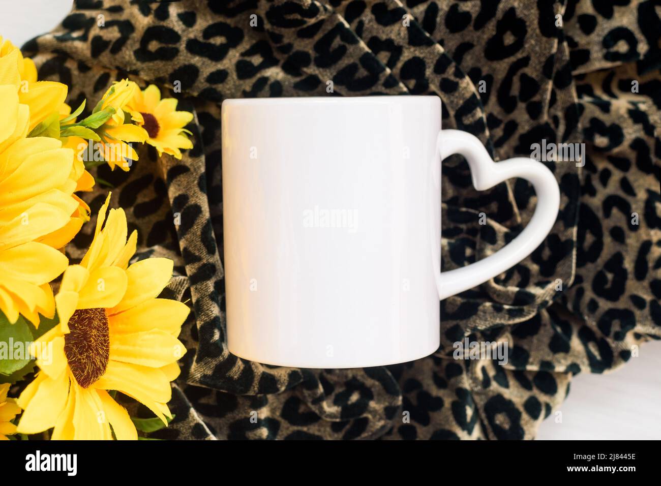 Tazza di caffè bianca mockup bianco e girasoli su soffice coperta leopardo animale, composizione flatlay, copyspace, vista dall'alto. Foto Stock