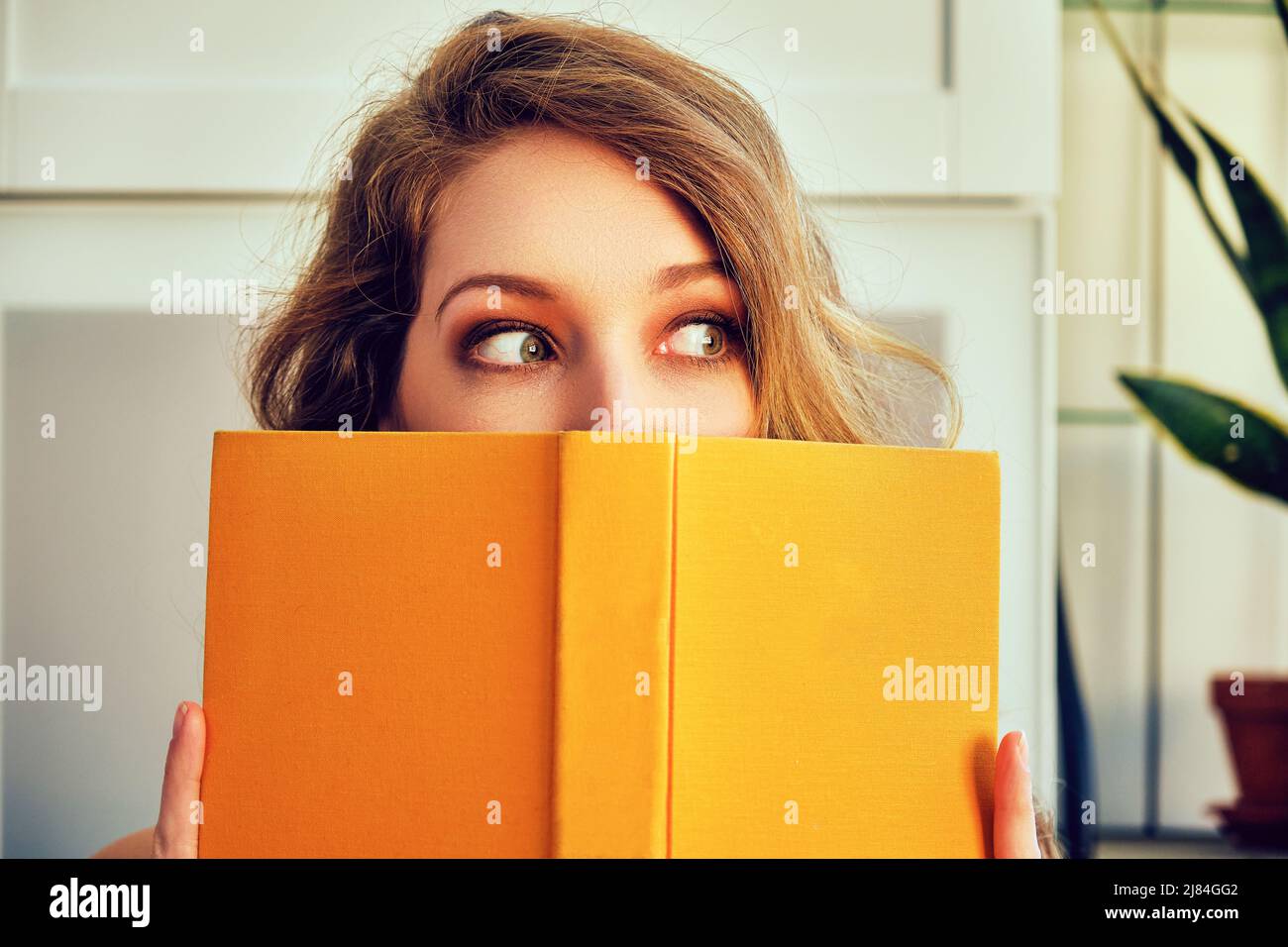 giovane donna che ricopre il volto con biblioteca di lettura del libro Foto Stock