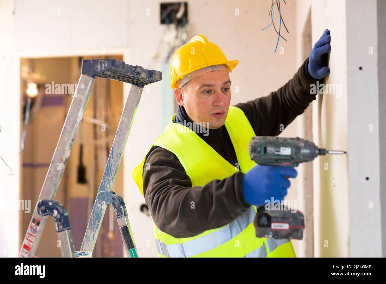 Addetto alla riparazione in uniforme con pistola a vite Foto Stock