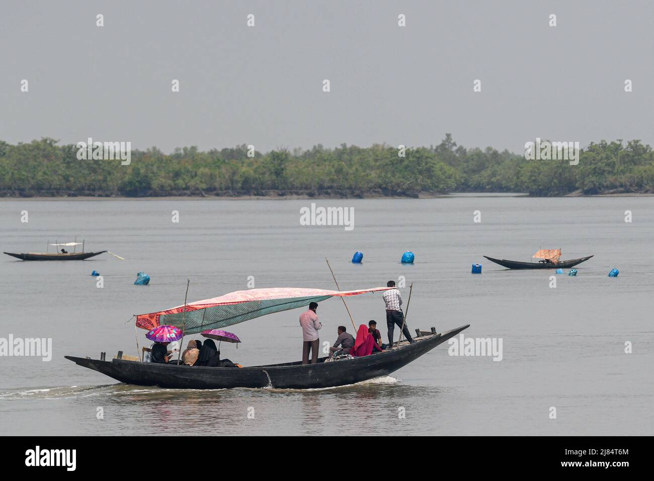 La gente ha visto attraversare il fiume Kholpatua con una barca vicino alla foresta Sundarban a Shyamnagar nel distretto di Satkhira. Migliaia di uomini e donne vanno nella foresta di Sundarbans nel Bangladesh meridionale ogni giorno per raccogliere miele, raccogliere legna da ardere, o catturare pesce, granchi e mettendosi a grande rischio per un attacco tigre. Il Bangladesh è uno dei paesi più vulnerabili agli effetti del cambiamento climatico. I rischi naturali regolari e gravi che il Bangladesh già soffre di cicloni tropicali, erosione fluviale, alluvione, frane e siccità sono tutti in grado di aumentare in intensità e frequenza come Foto Stock
