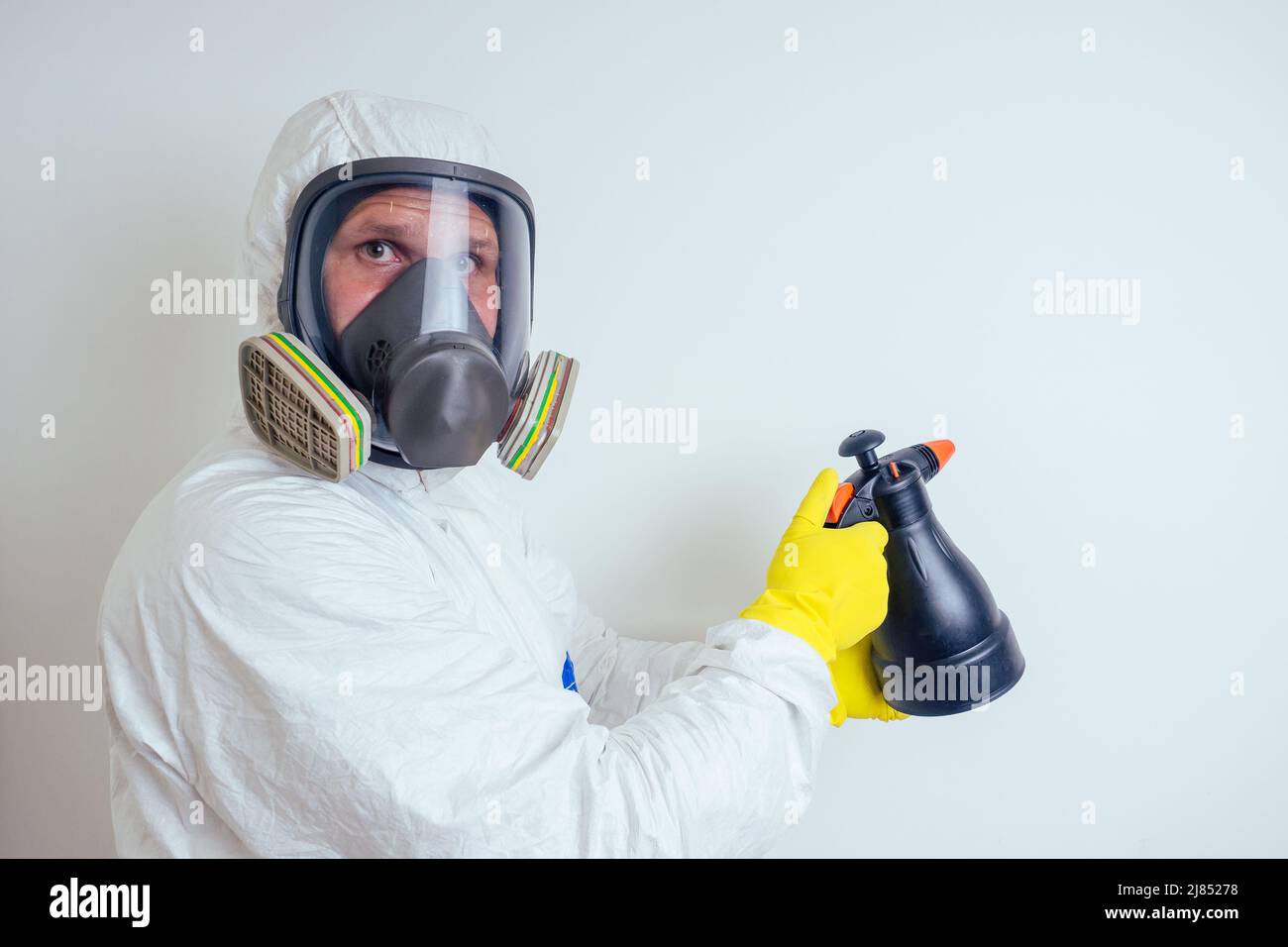 il lavoratore di controllo di peste spruzzando pesticidi con spruzzatore in appartamento copia spase sfondo bianco pareti Foto Stock