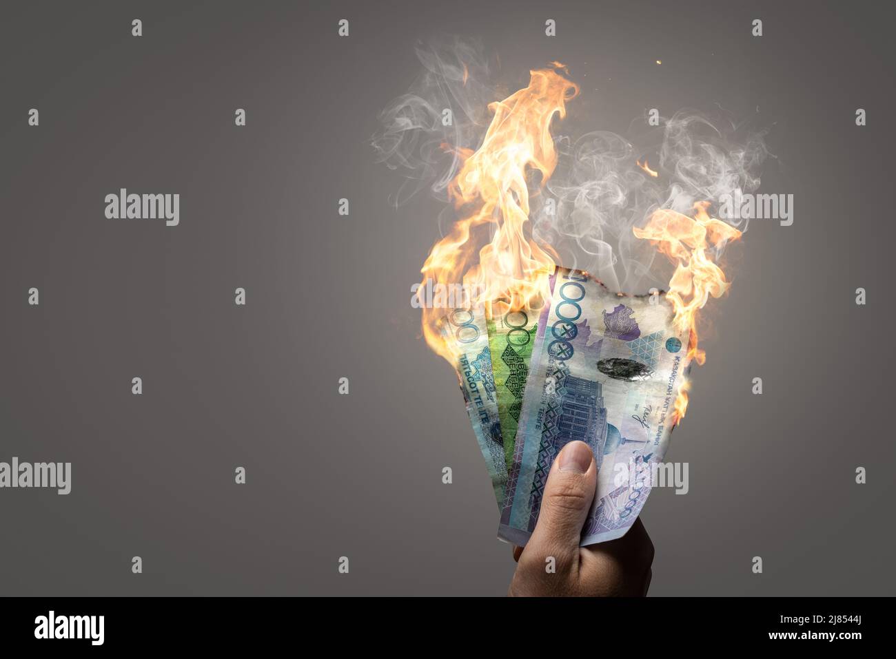 Bruciare le banconote in manica kazako tenute da una mano Foto Stock