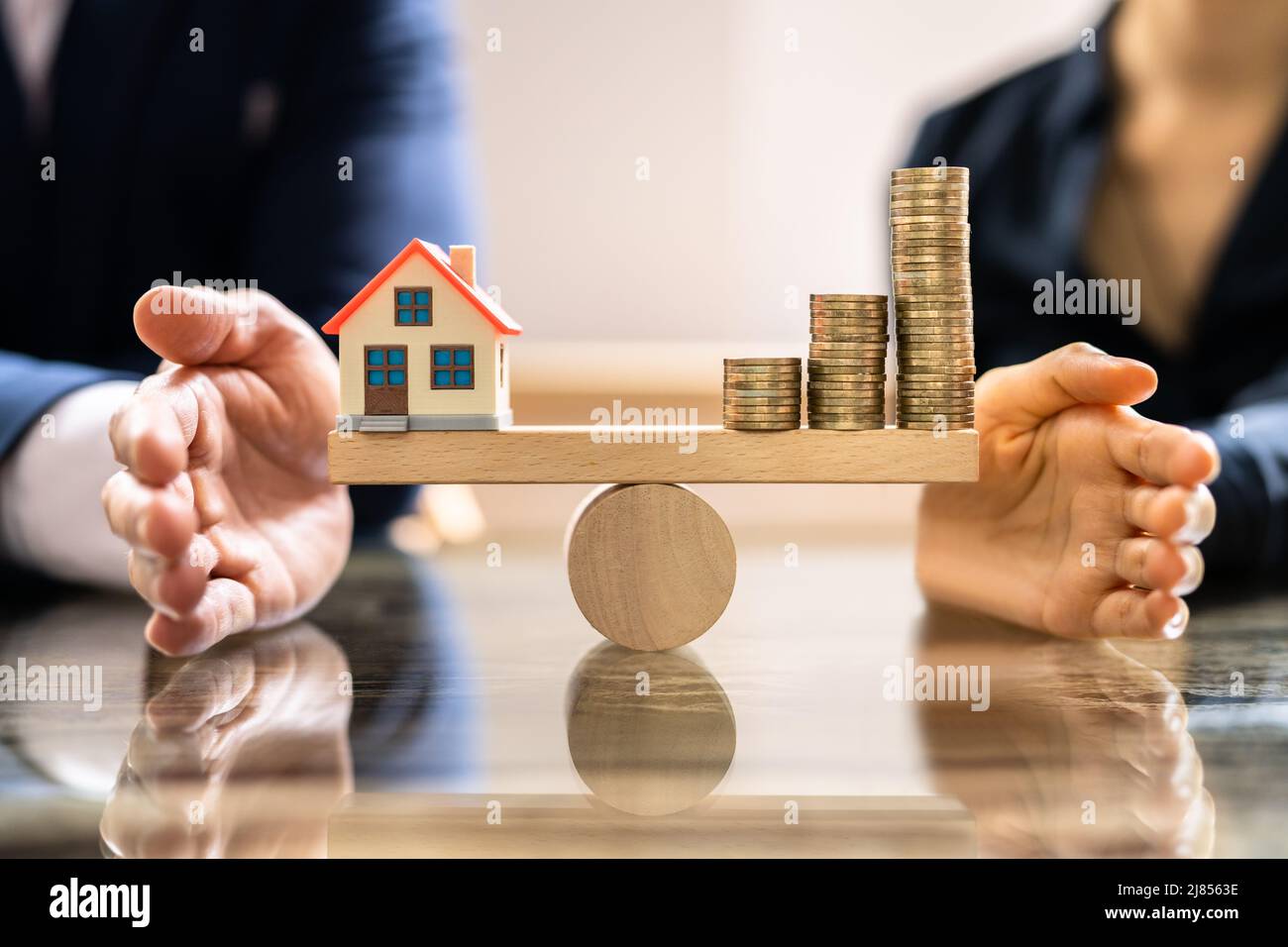 Accoppiare la mano proteggere le monete impilate e casa per il modello in piccole casette di legno altalena Foto Stock