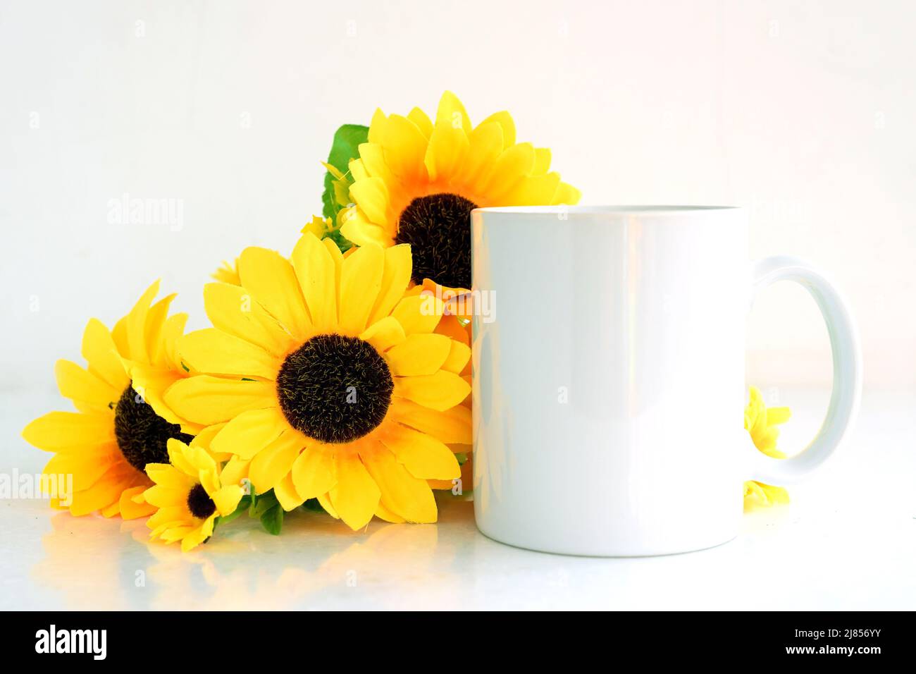 Caffè bianco mockup tazza con bouquet di girasoli gialli, copyspace. Foto Stock