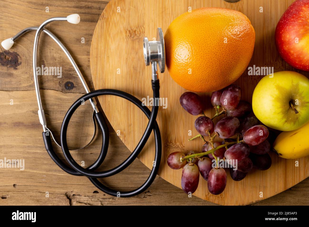 Direttamente sopra shot di mele con arancia e uva su vassoio di legno da stetoscopio su tavola Foto Stock