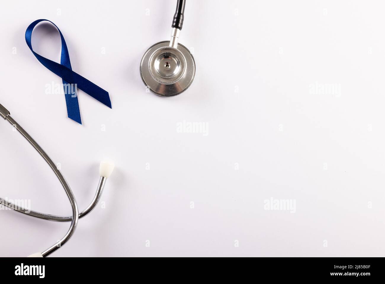 Vista dall'alto del nastro blu di consapevolezza del cancro dello stomaco e dello stetoscopio su sfondo bianco Foto Stock