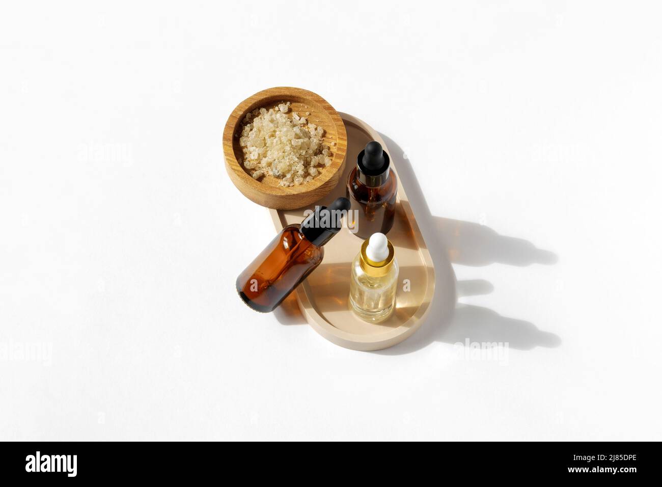 Bottiglie di vetro alla moda con olio su fondo bianco. Bottiglie cosmetiche ambrate, scrub al sale. Prodotti naturali di bellezza. Minimalismo. Medicina di erbe. Benessere Foto Stock