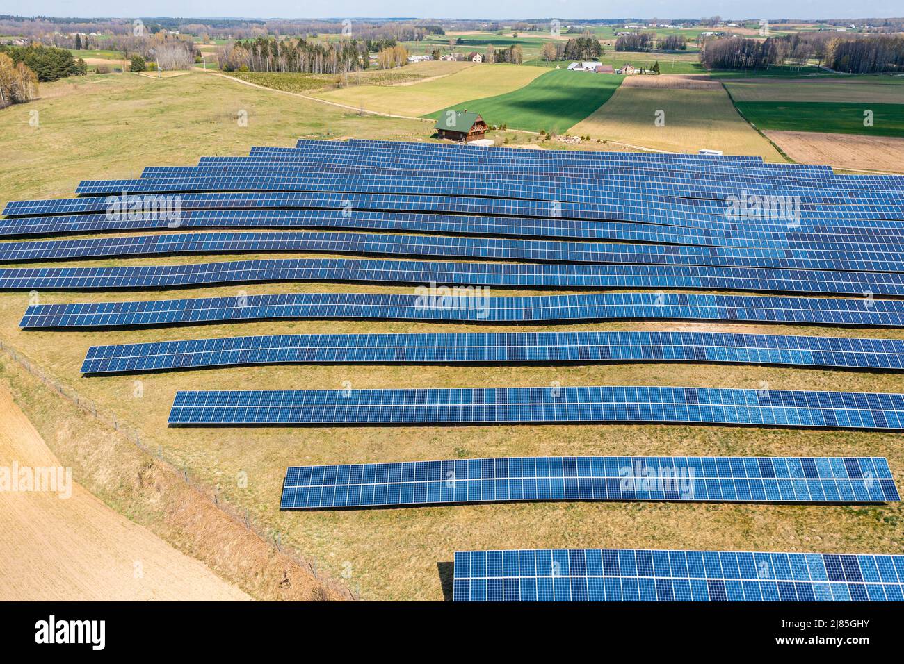 Vista aerea dell'azienda agricola solare, file di pannelli fotovoltaici da una piccola casa Foto Stock