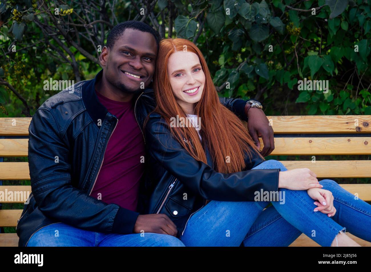 afro american uomo seduto su sedia a rotelle, la sua ragazza zenzero rossa girello rolling nel parco autunnale. avendo data romantica Foto Stock