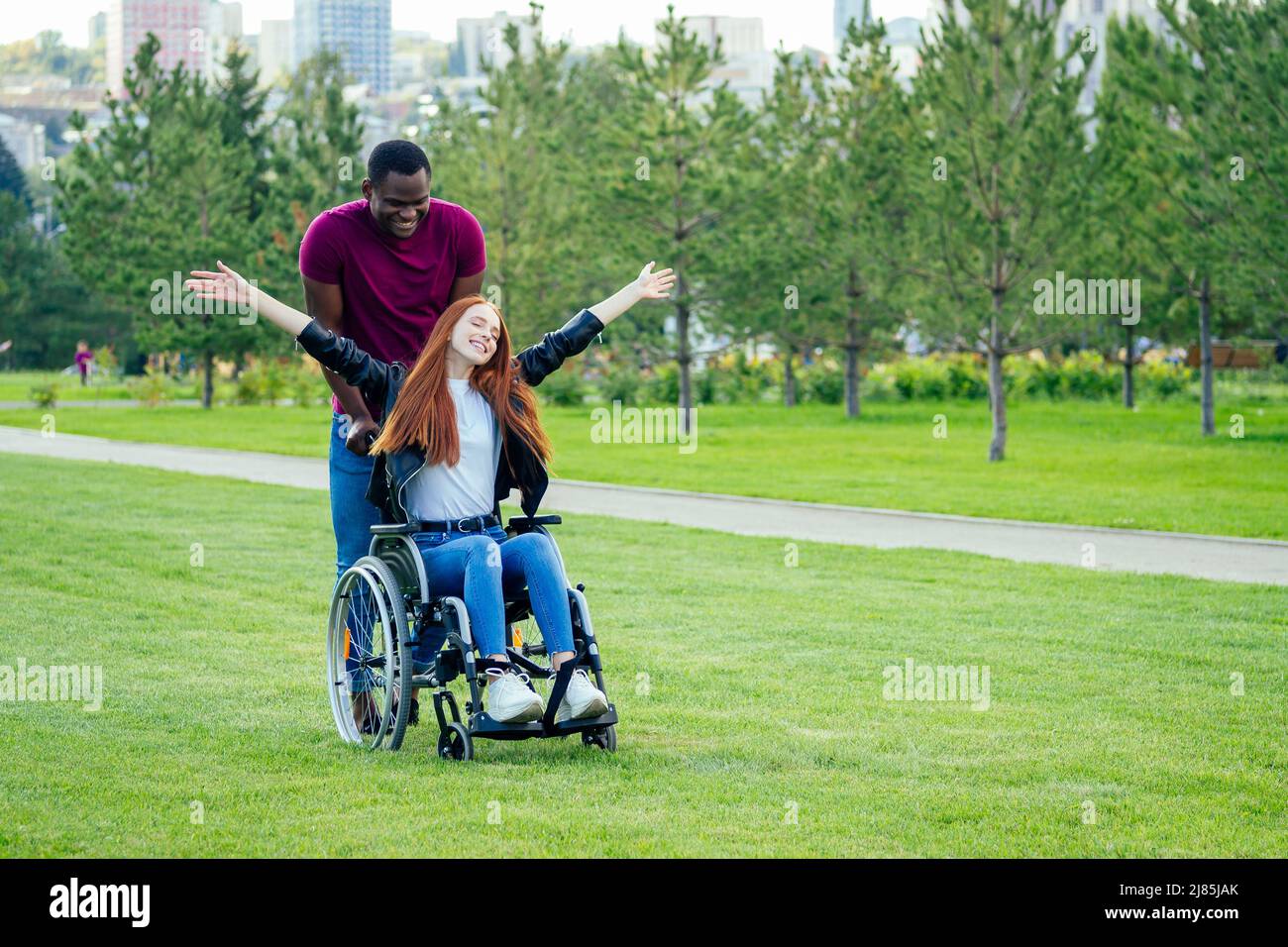 afro american uomo matrimonio proposta dando un anello al suo rosso zenzero girlfriend.she seduta su sedia ruota e sorpreso e stupito Foto Stock