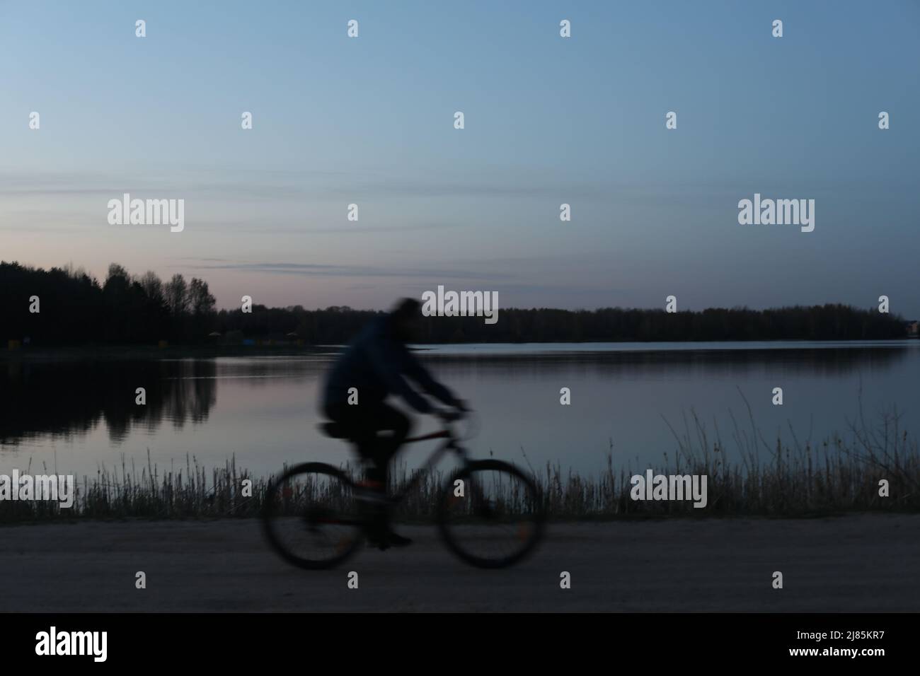 Silhouette di un bicyclist sulla spiaggia al tramonto Foto Stock