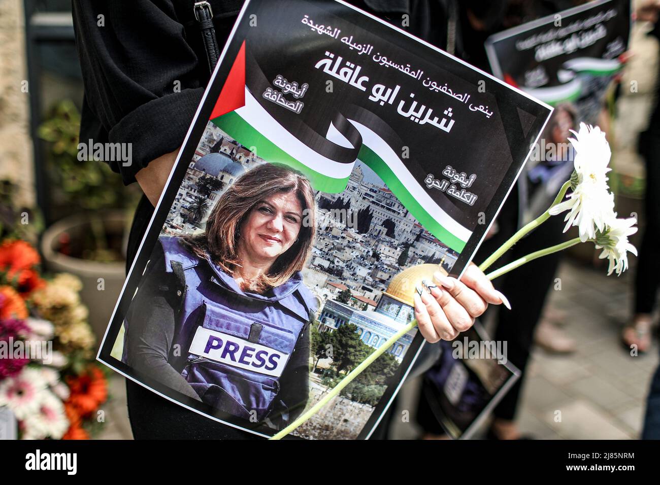 Gerusalemme. 13th maggio 2022. Un manifestante tiene fiori e un poster del giornalista al Jazeera Shireen Abu Akleh durante una protesta fuori dall'ospedale francese per denunciare la sua uccisione. Abu Akleh, 51, figura di spicco nel servizio di stampa arabo del canale al-Jazeera, è stato ucciso il 11 maggio durante un confronto tra soldati israeliani e palestinesi nella città di Jenin, in Cisgiordania. Credit: Ilia Yefimovich/dpa/Alamy Live News Foto Stock