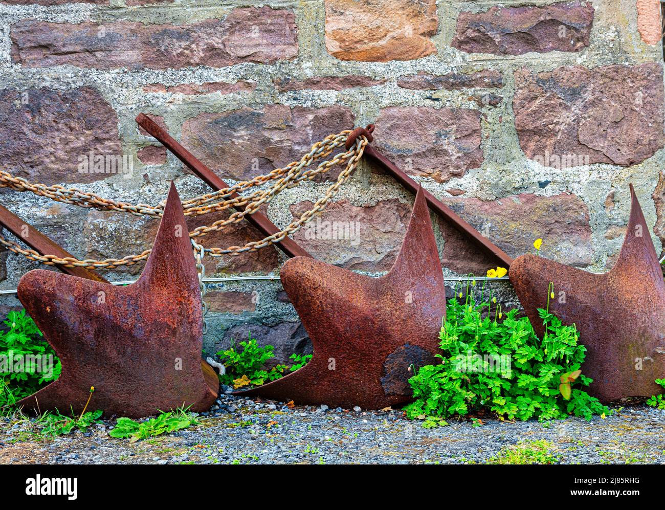 Tre ancore e catene in metallo arrugginito nel villaggio Highland di Plockton, Scozia Foto Stock