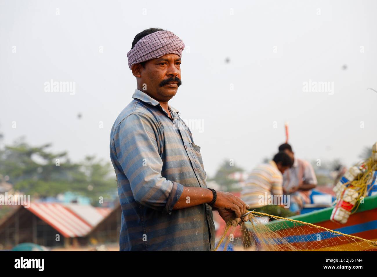 Ritratto di pescatore in piedi in barca con rete da pesca, Tangassery, Kerala, India. Foto Stock