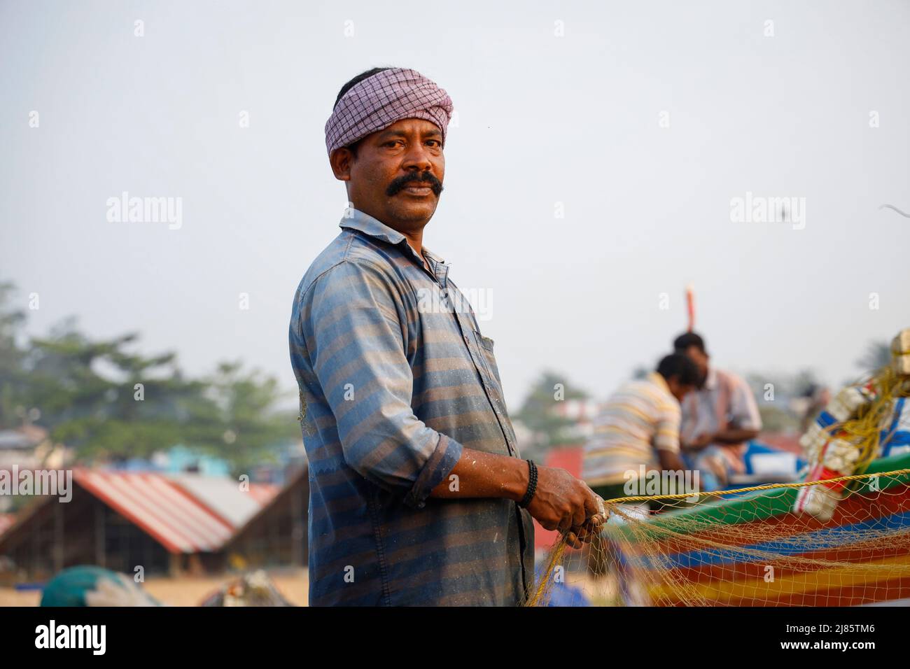 Ritratto di pescatore in piedi in barca con rete da pesca, Tangassery, Kerala, India. Foto Stock
