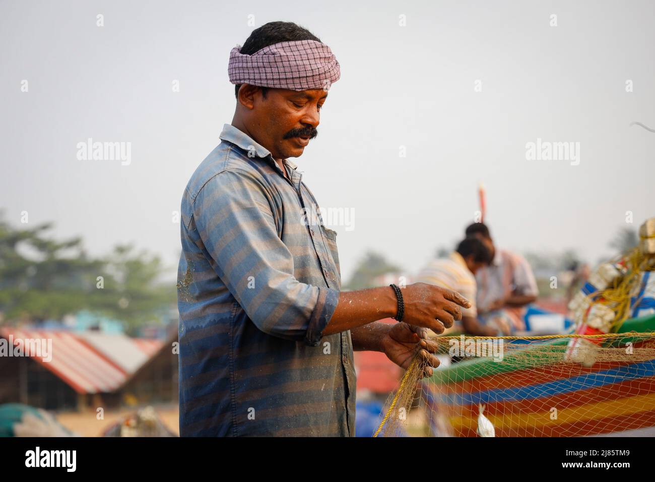 Ritratto di pescatore in piedi in barca con rete da pesca, Tangassery, Kerala, India. Foto Stock