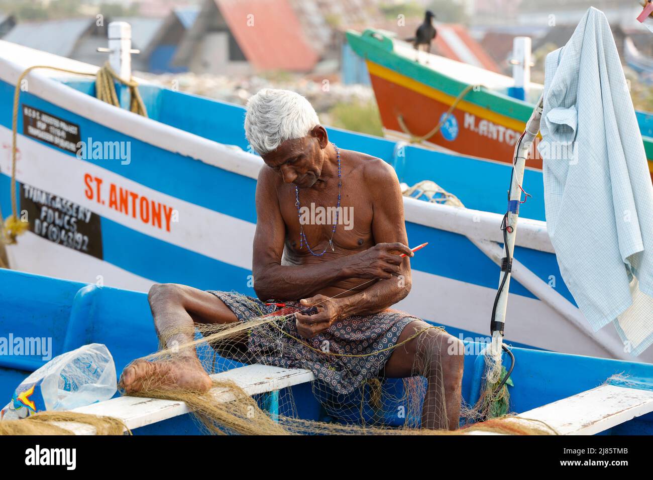 Ritratto di vecchio pescatore che menda la sua rete da pesca, Tangassery, Kerala, India. Foto Stock