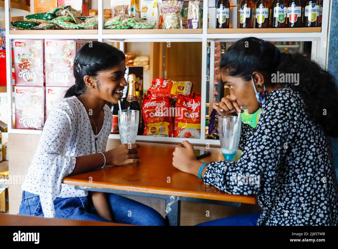 Due ragazze adolescenti indiane che bevono softdrink di colore blu, Tangassery, Thangassery, Kerala, India. Foto Stock