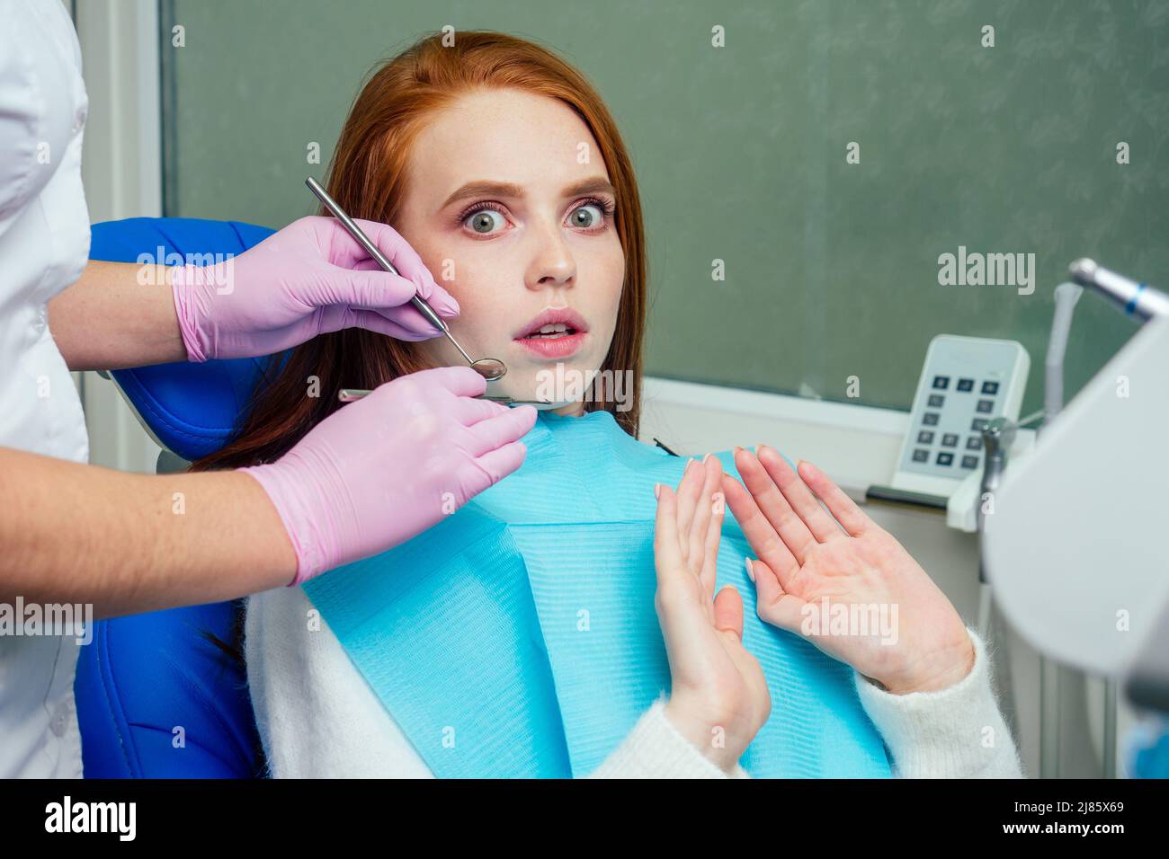 lo zenzero rosso ha sollecitato la paziente femminile paura al check-up esame dentale in clinica Foto Stock