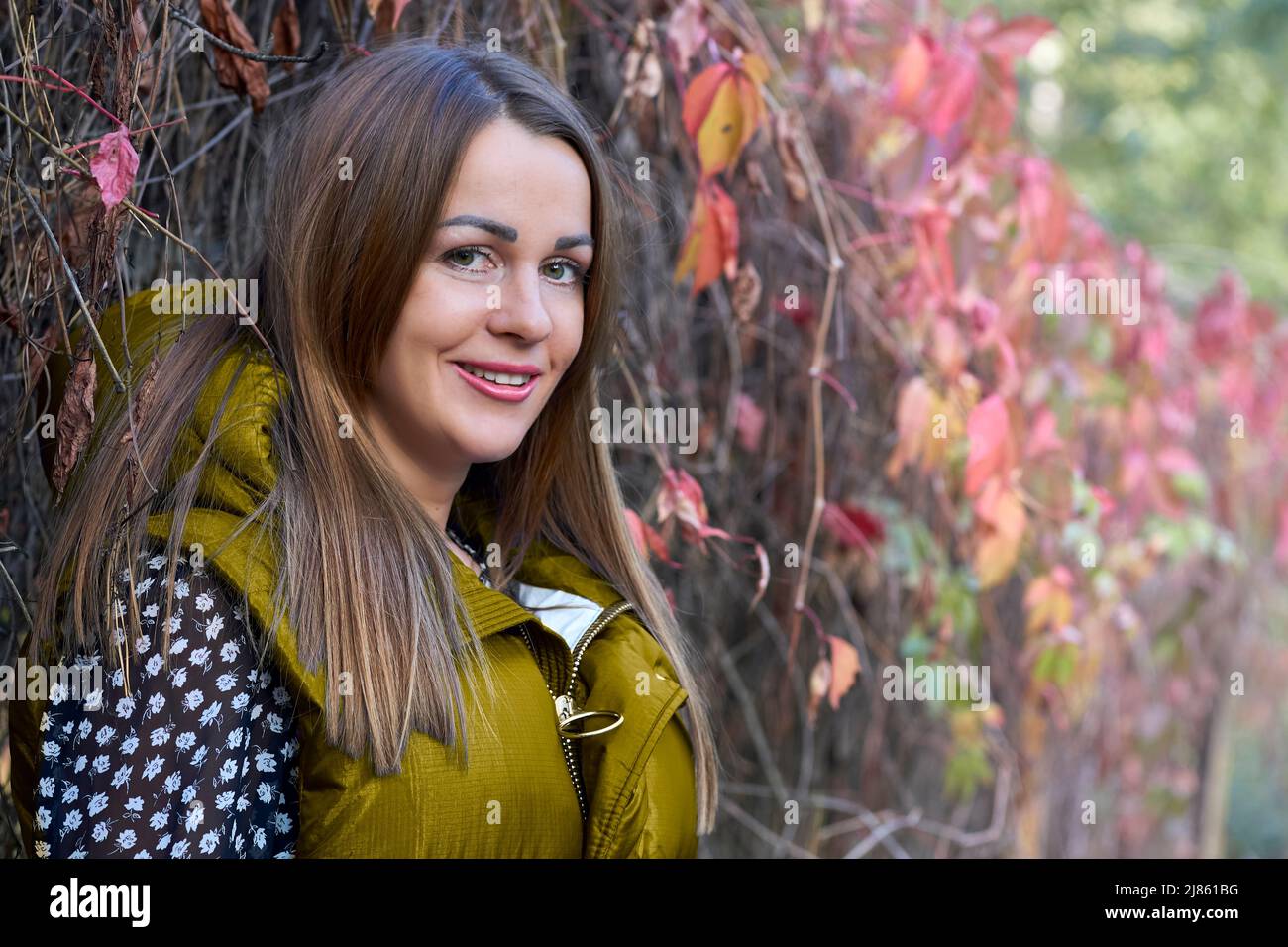Ragazza sorridente carina in un gilet blu e aranci rossi Foto Stock