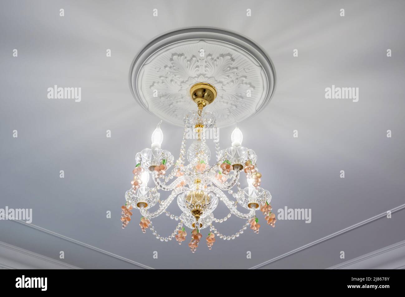 lampadario alla moda in un interno luminoso appeso sotto il soffitto in palazzo, appartamento o hotel Foto Stock