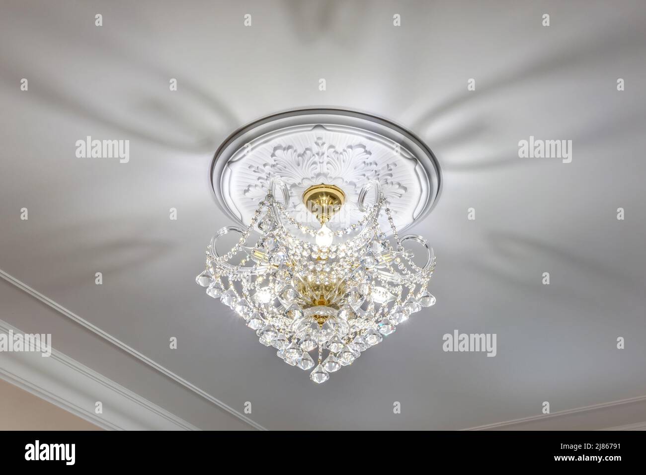 lampadario alla moda in un interno luminoso appeso sotto il soffitto in palazzo, appartamento o hotel Foto Stock