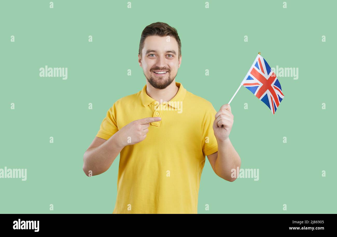 Il giovane felice che sta imparando l'inglese sta tenendo la bandiera del Regno Unito e sorridendo Foto Stock