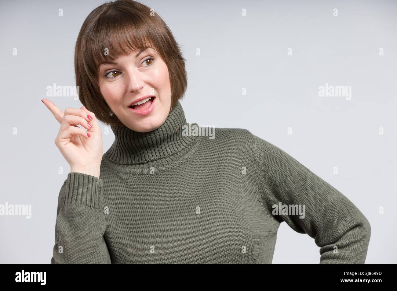Giovane sorridente / felice donna ha un'idea e si alza il dito puntatore Foto Stock