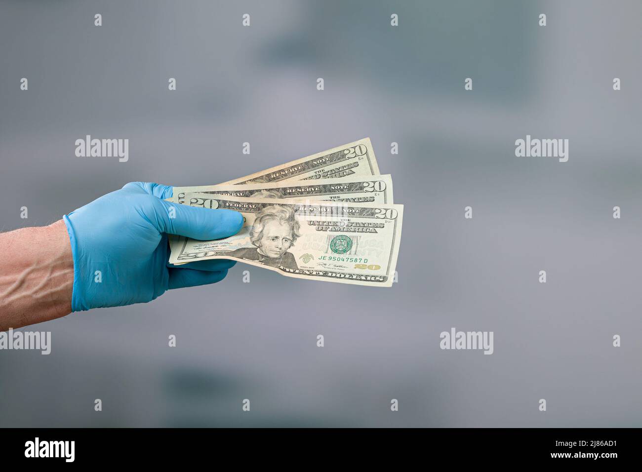 mano degli uomini in guanti medici con un mazzo di bollette del dollaro Foto Stock