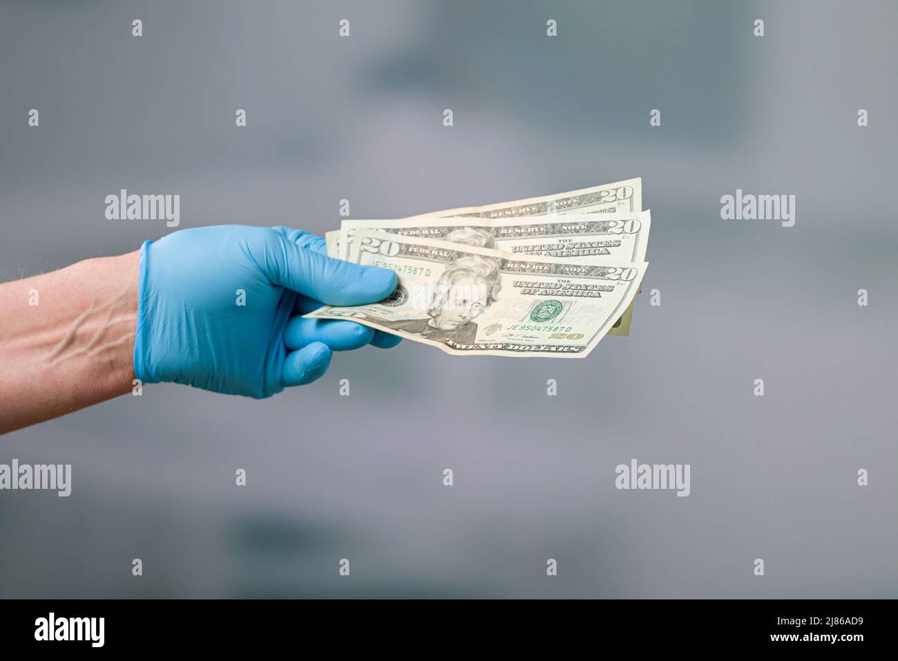 mano degli uomini in guanti medici con un mazzo di bollette del dollaro Foto Stock