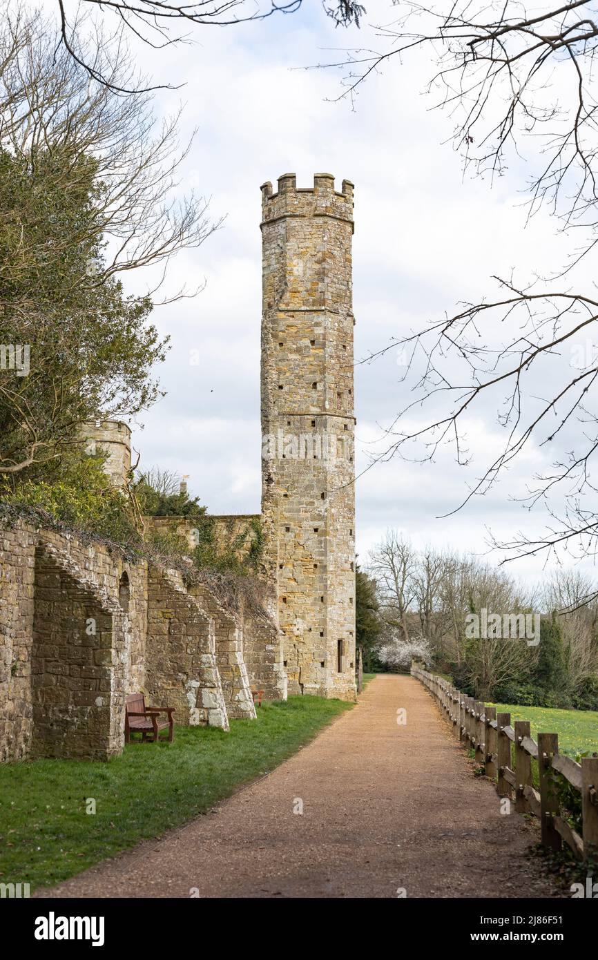 Guardando lungo un sentiero in pietra ad un'alta torre in pietra color crema alla fine di un muro di un castello Foto Stock