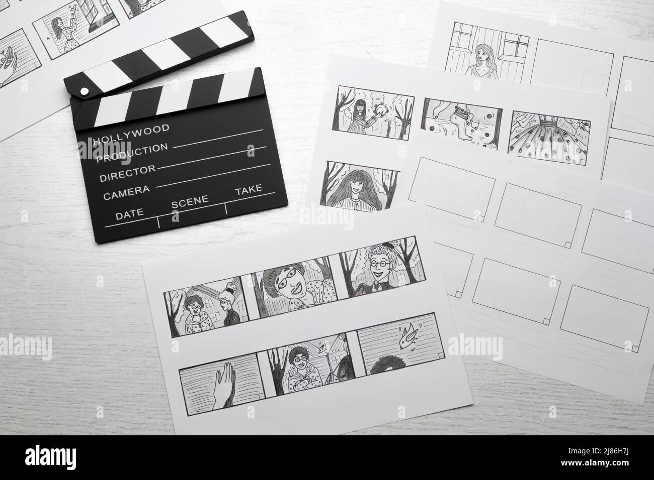 Schizzi disegnati storyboard di personaggi per un film o cartoon con un clapperboard sul desktop. Foto Stock