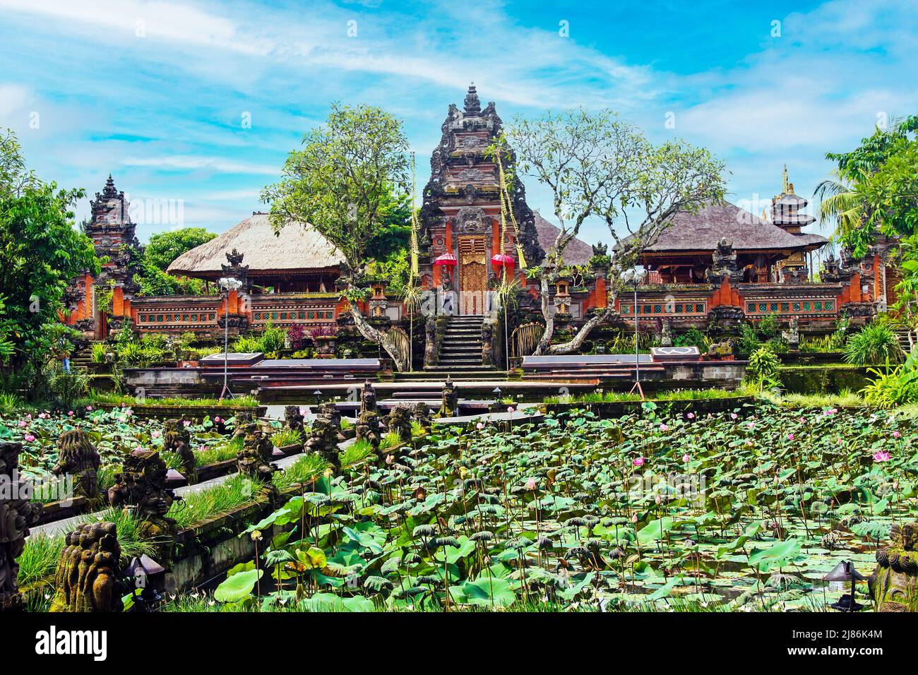 Bel paesaggio asiatico, loto fiore stagno acqua giardino, antico tempio rosso indù, cielo blu - Ubud, pura Taman Saraswati (Water Palace), Bali, Indo Foto Stock