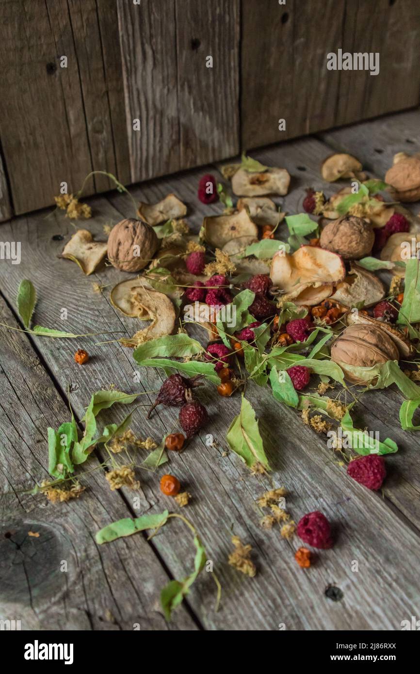 Deliziose prelibatezze essiccate. Pezzi secchi di tiglio, fianchi di rose, pere, lamponi, mele e noci snack su sfondo di legno. Foto Stock