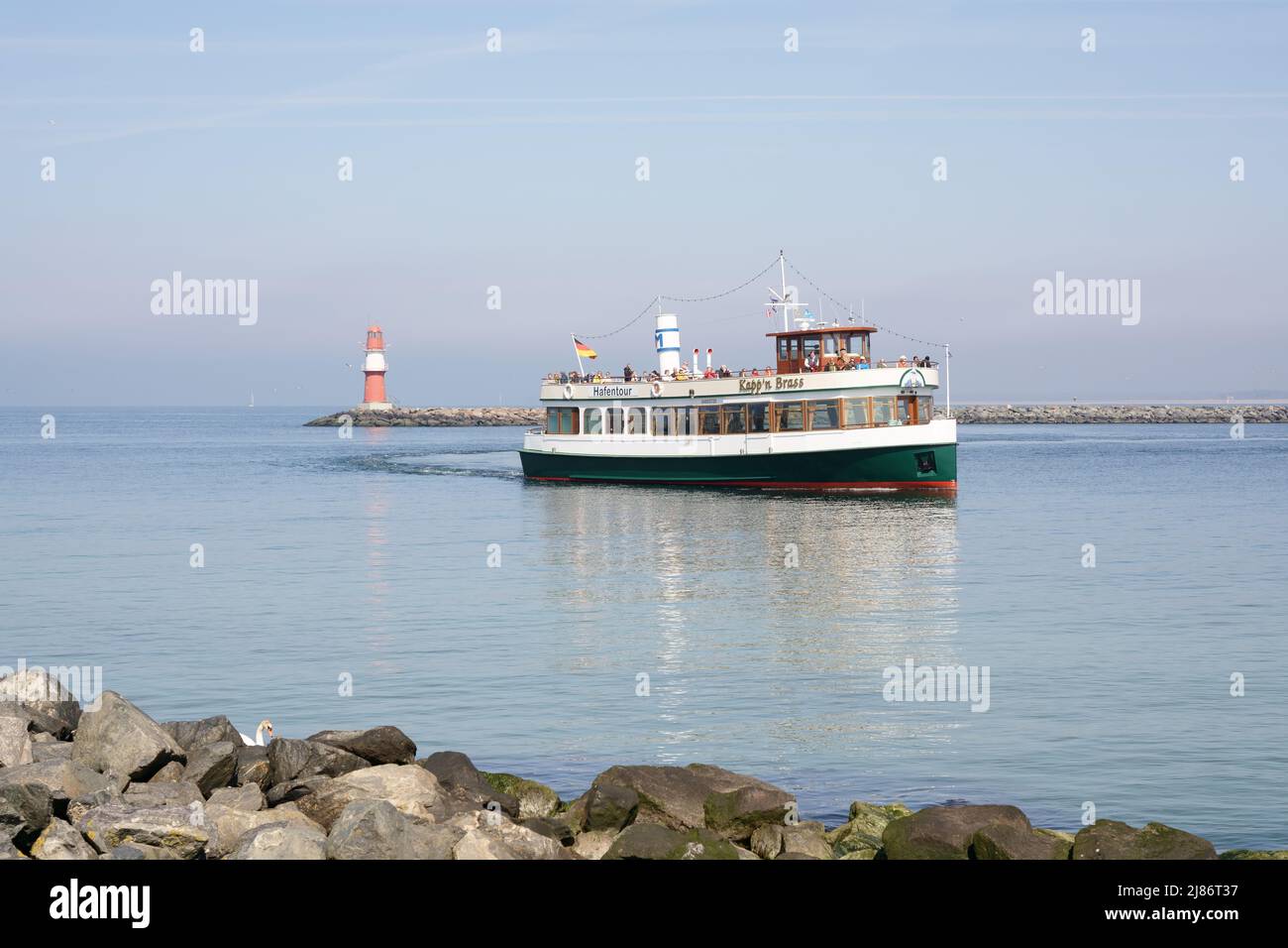 Warnemünde sul Mar Baltico a Mecklenburg-Vorpommern, Germania. Faro e barca turistica nel porto. Foto Stock