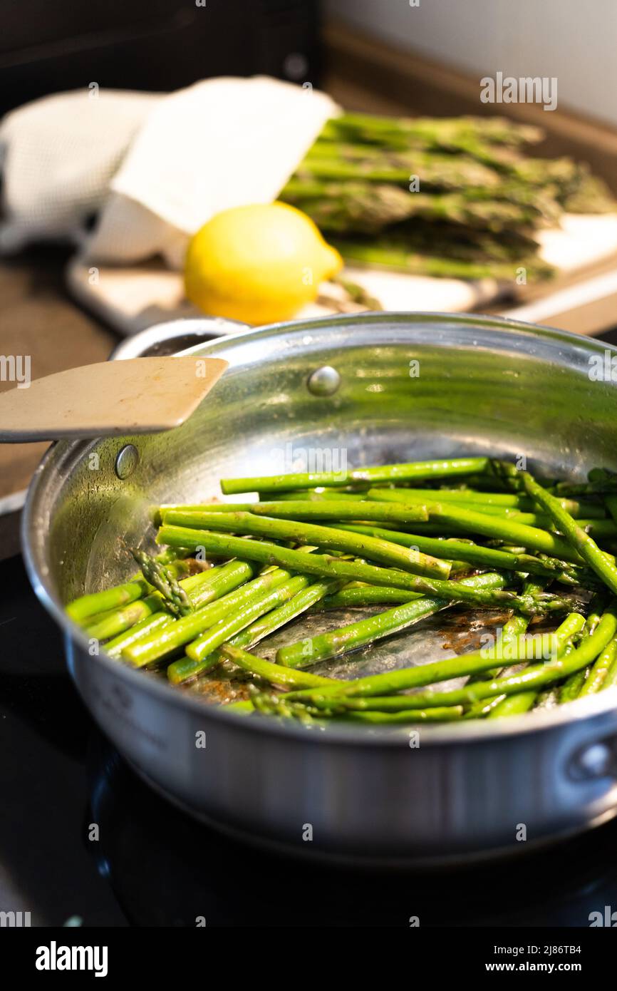 Cottura degli asparagi. Arrostire i germogli di asparagi in una padella con burro e aglio. Cibo e dieta sani. Foto Stock