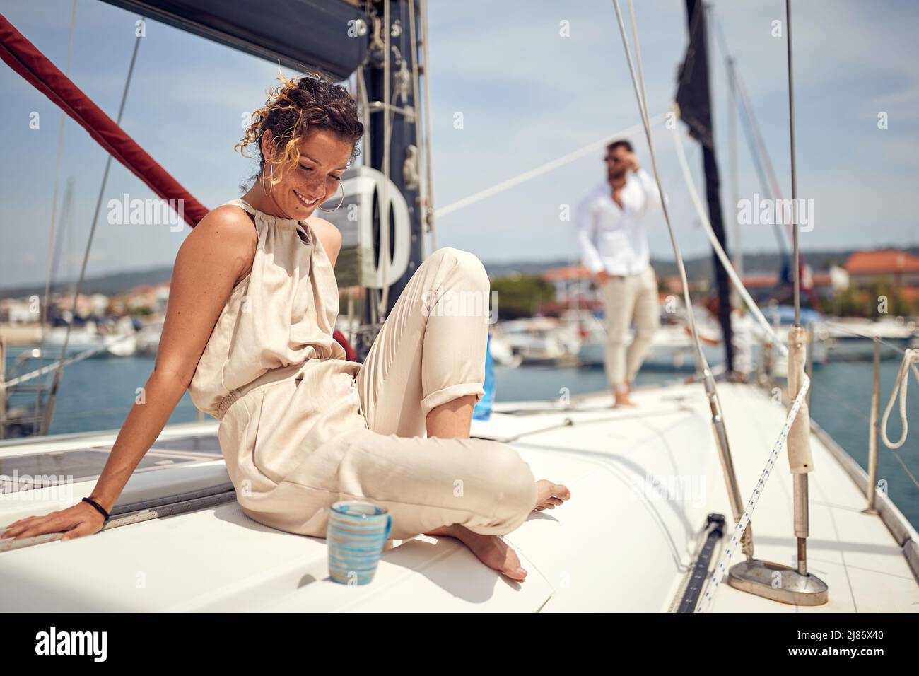 Una ragazza bella e giovane è seduta su uno yacht e godersi il sole in una bella giornata estiva. Estate, mare, vacanza, rapporto Foto Stock