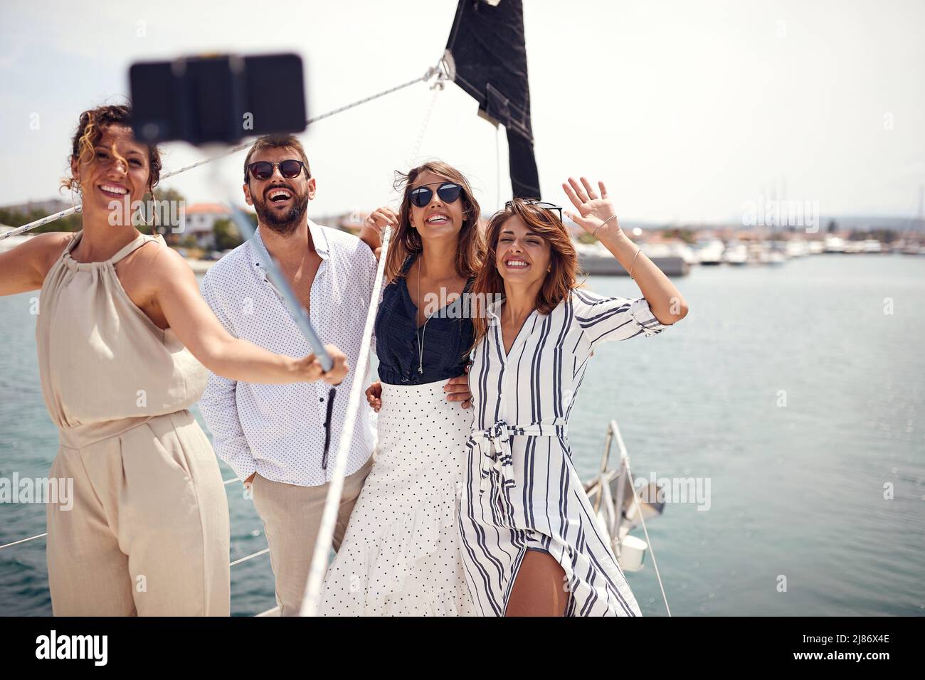 Un gruppo di giovani modelli belli sta prendendo un selfie sul ponte dello yacht in una bella giornata estiva sul mare. Estate, mare, vacanza, amicizia Foto Stock