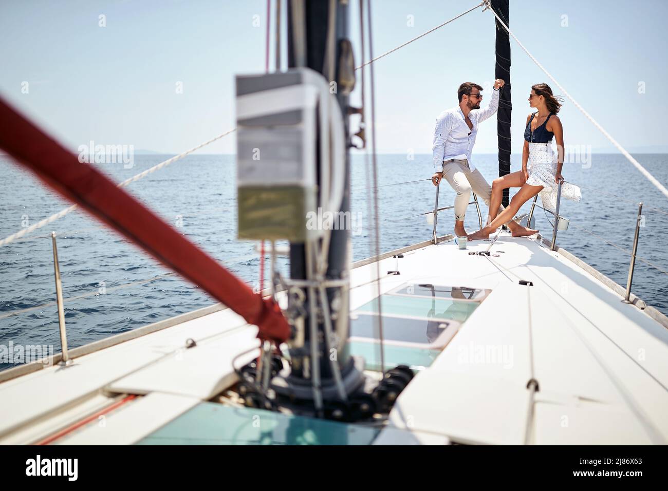 Una giovane coppia sta chiacchierando e posando per una foto sulla prua dello yacht mentre si gode un giro in una bella giornata di sole sul mare. Estate, mare, vacanza Foto Stock