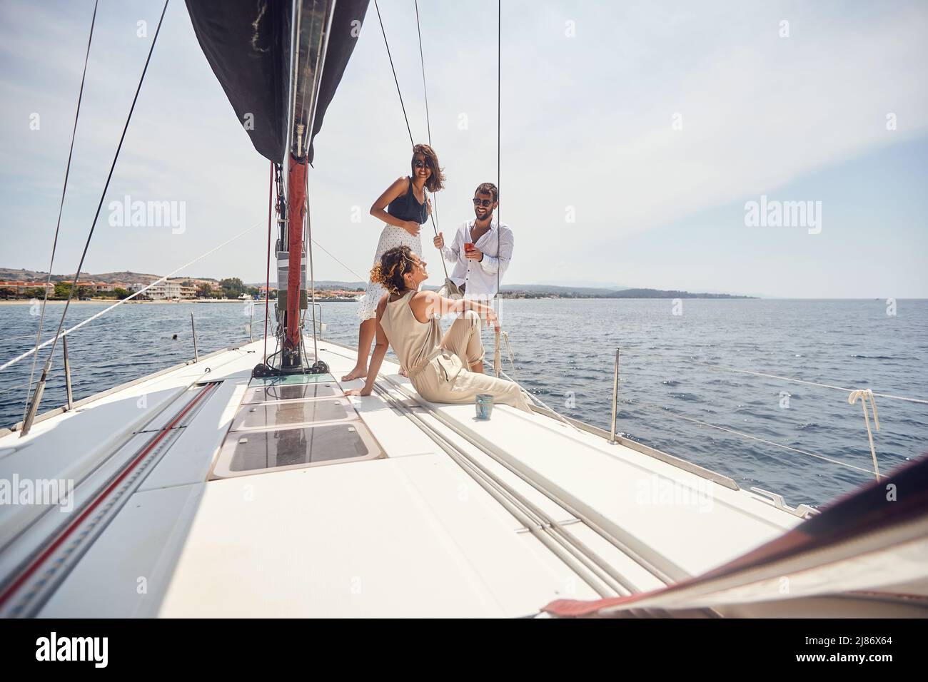 Un gruppo di giovani modelli belli sta godendo il sole ed il vento mentre sta posando per una foto sul ponte dello yacht in una bella giornata estiva il th Foto Stock