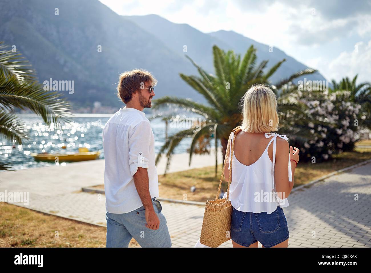 Una giovane coppia sta godendo una passeggiata sul molo in una bella giornata di sole sul mare. Amore, rapporto, vacanza, mare Foto Stock