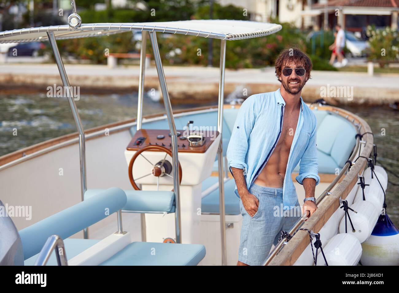 Uomo attraente con maglia aperta in barca a vela. Vacanza sport acquatici, estate all'aperto. Vacanza, tempo libero, stile di vita concetto Foto Stock