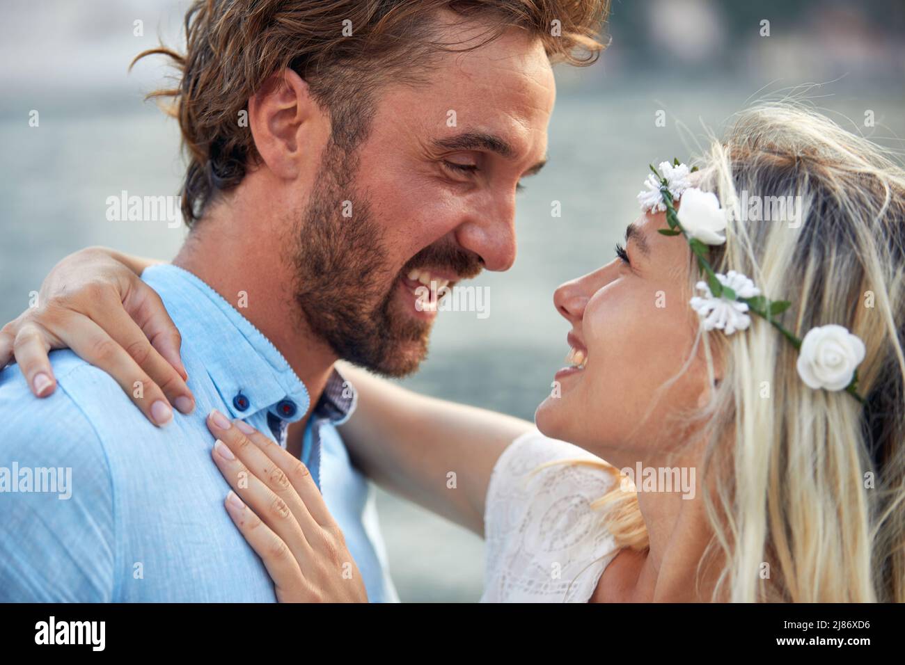 bella sposa sorridente in abito bianco gode l'abbraccio del suo uomo Foto Stock