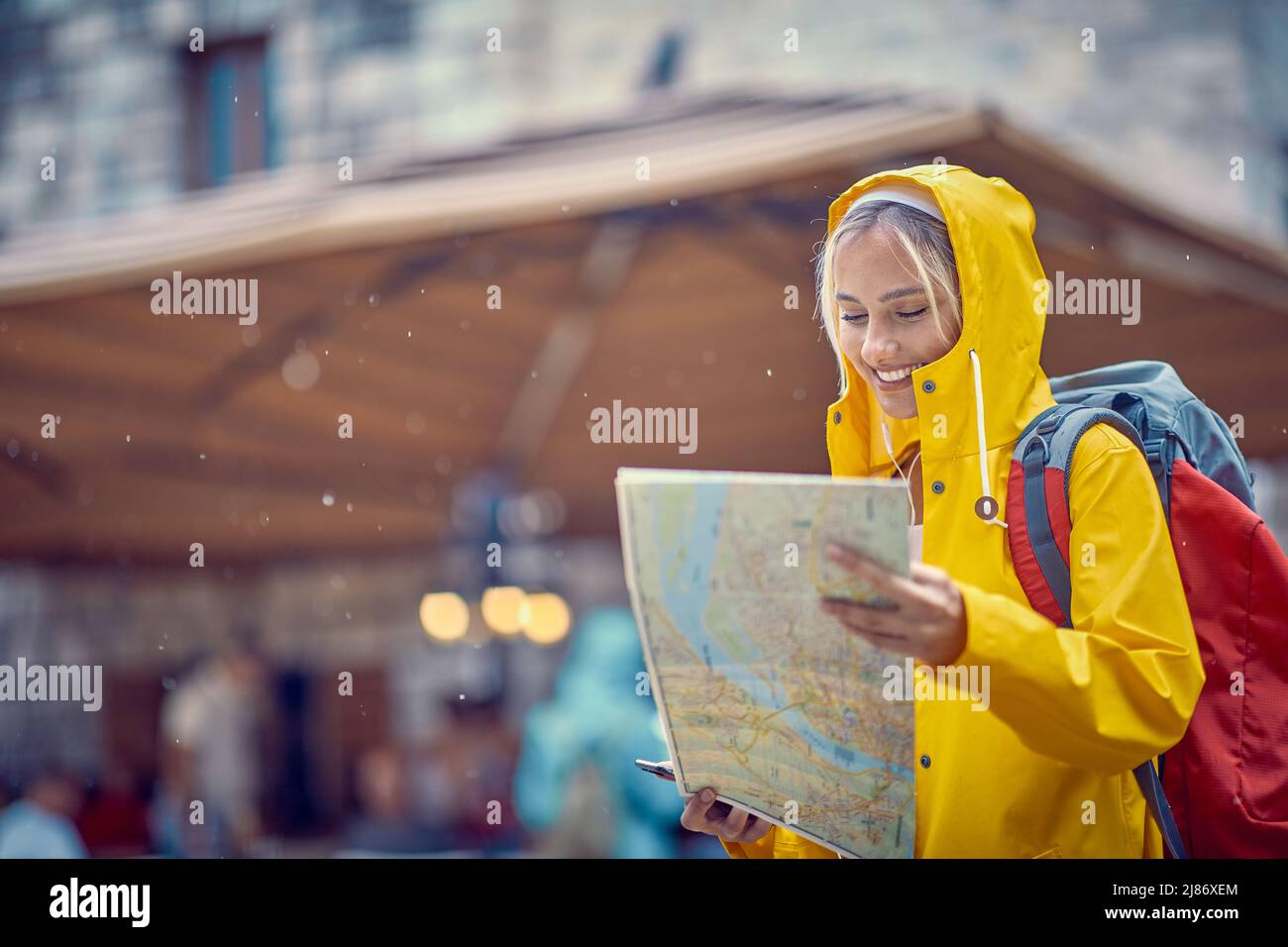 Una giovane ragazza segue la mappa mentre cammina per la città vecchia in una giornata piovosa durante una vacanza sul mare. Vacanze, mare, turismo Foto Stock