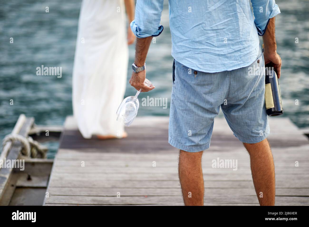 Una giovane coppia in momenti romantici con vino sul molo in una bella giornata di sole sul mare. Amore, rapporto, vacanza, mare Foto Stock