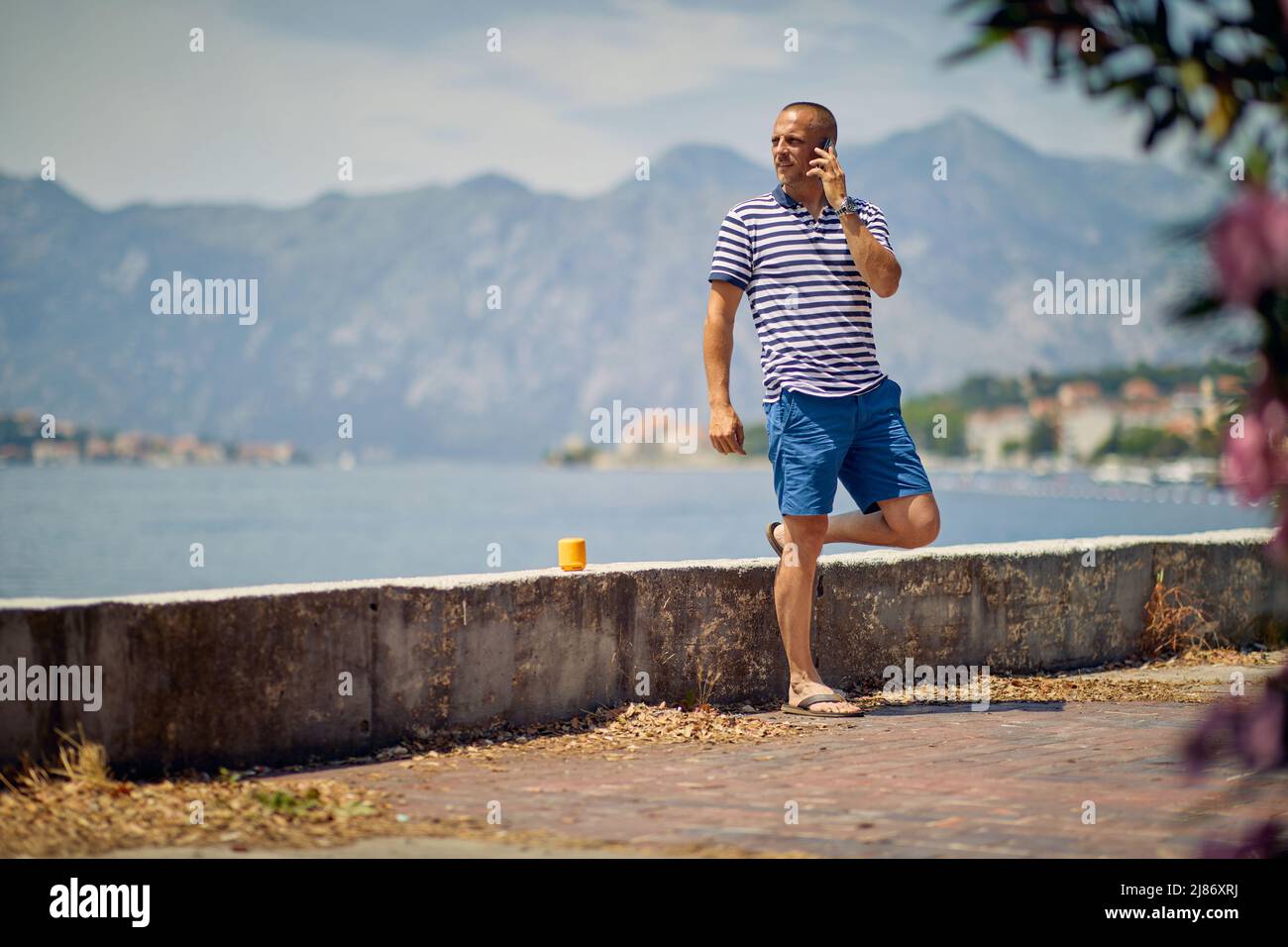 Uomo in piedi sul dock, per effettuare una chiamata. Uomo d'affari con smartphone. Concetto di lavoro, viaggio, stile di vita. Foto Stock